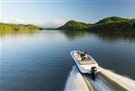 Bayliner VR6 - 2023 Bayliner VR6 boat cruising on a serene lake with lush green hills.