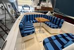 Vanquish 26 - 2021 Vanquish 26 boat with blue-striped seating and wooden table in a marina setting.