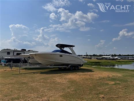 Chaparral 264 Sunesta - 2012 Chaparral 264 Sunesta boat on trailer, parked near RVs by a lake.