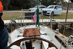 Pearson 35 - 1971 Pearson 35 sailboat cockpit with American flag, docked near parked cars.