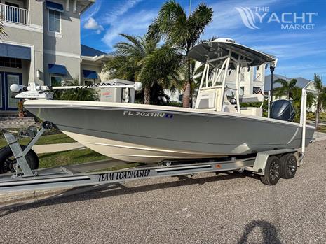 Pathfinder 2500 Hybrid - 2019 Pathfinder 2500 Hybrid boat on trailer, parked near palm trees and house.