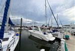 Sea Ray Sundancer - 1998 Sea Ray Sundancer docked at a marina, surrounded by sailboats under a cloudy sky.