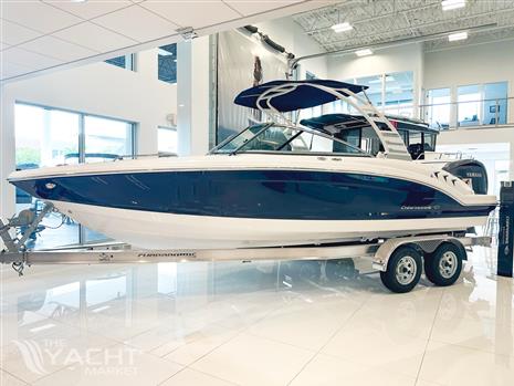 Chaparral 23 SSi OB - 2024 Chaparral 23 SSi OB boat in showroom, blue and white design on trailer.