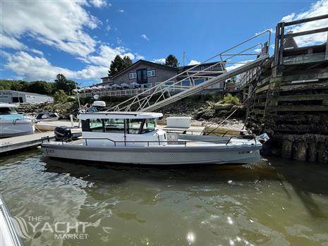 Axopar 28 - 2016 Axopar 28 boat docked by a wooden pier under a sunny sky.