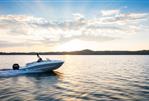 Bayliner VR5 - 2024 Bayliner VR5 speedboat cruising on a serene lake at sunset.