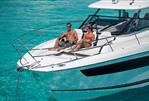 Jeanneau Leader 12.5 WA - 2023 Jeanneau Leader 12.5 WA boat with couple relaxing on deck in clear blue water.