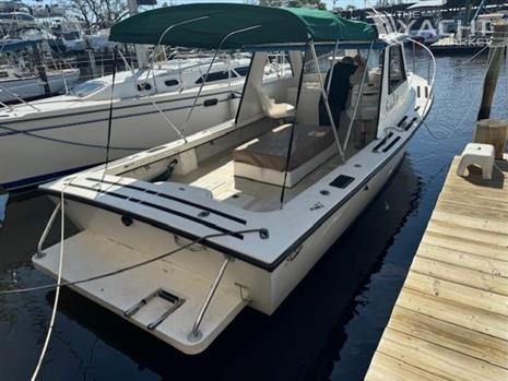 Sabalo 26 - 2001 Sabalo 26 boat docked with green canopy, spacious deck, and nearby marina.