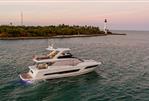 Prestige 690 - 2025 Prestige 690 yacht cruising near a lighthouse at sunset.