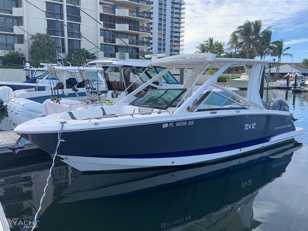 Chaparral 280 OSX - 2020 Chaparral 280 OSX boat docked in a marina with modern buildings in the background.