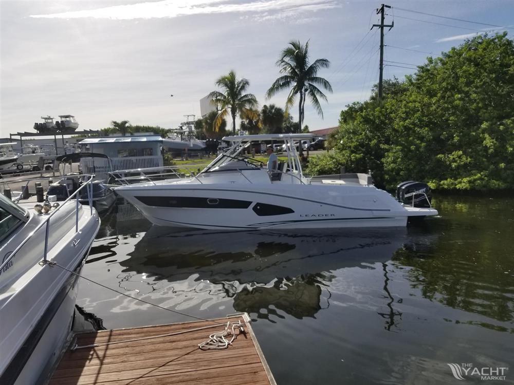 Jeanneau Leader 10.5 - 2018 Jeanneau Leader 10.5 boat docked in a marina with palm trees.