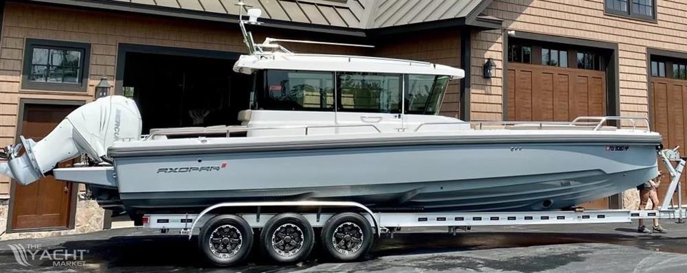 Axopar 28 CABIN - 2019 Axopar 28 CABIN boat on trailer, parked outside a garage.