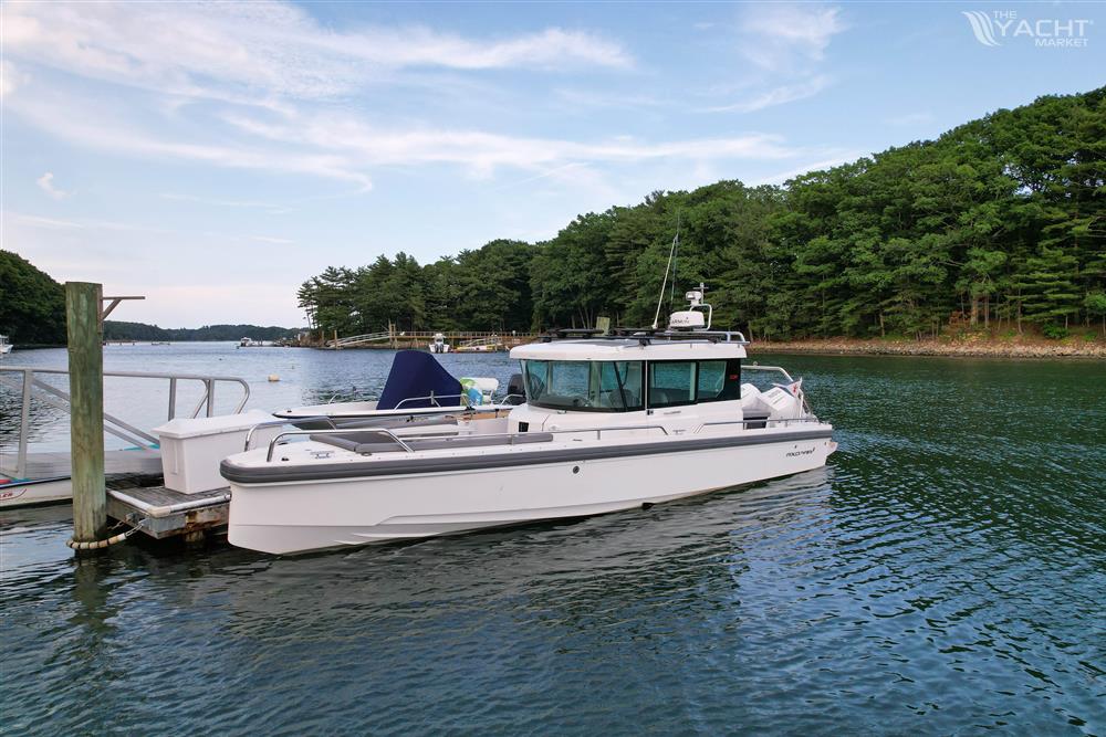 Axopar 28 CABIN - 2020 Axopar 28 CABIN boat docked on a serene lake with lush green trees.