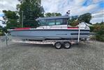 Axopar 28 - 2022 Axopar 28 boat on trailer, parked outdoors, with trees in the background.