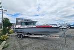 Axopar 28 - 2022 Axopar 28 boat on trailer in a gravel lot under cloudy sky.