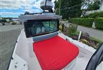 Axopar 28 - 2022 Axopar 28 boat with red cover, docked near lush greenery.