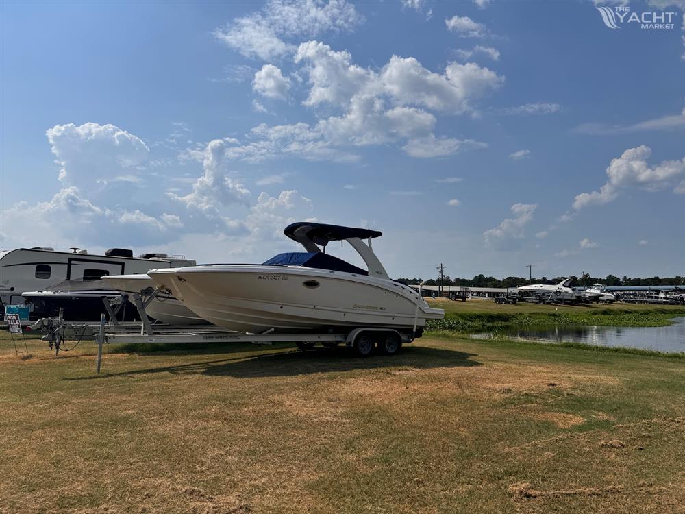 Chaparral 264 Sunesta - 2012 Chaparral 264 Sunesta boat on trailer, parked near RVs by a lake.