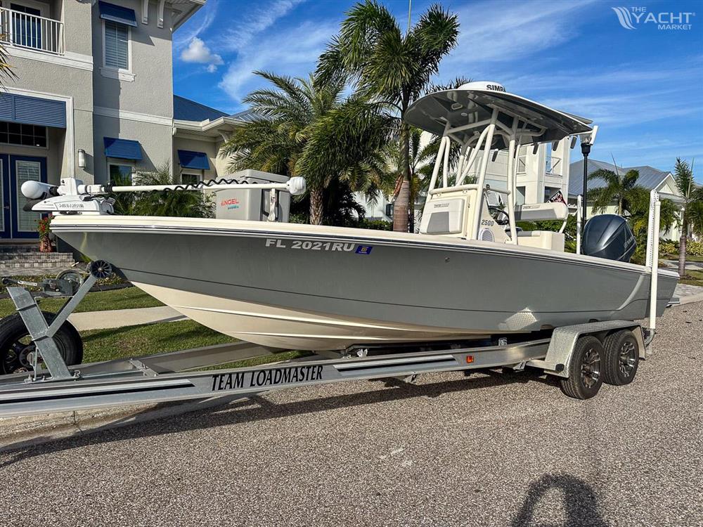 Pathfinder 2500 Hybrid - 2019 Pathfinder 2500 Hybrid boat on trailer, parked near palm trees and house.