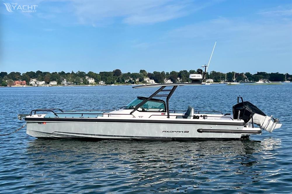 Axopar 28 T-Top - 2023 Axopar 28 T-Top boat on calm water with scenic shoreline background.