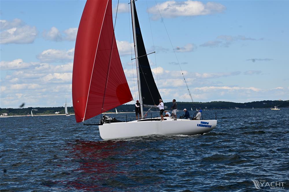 M.A.T. 1070 - Sailing yacht M.A.T. 1070, 2024 model, with red and black sails on open water.