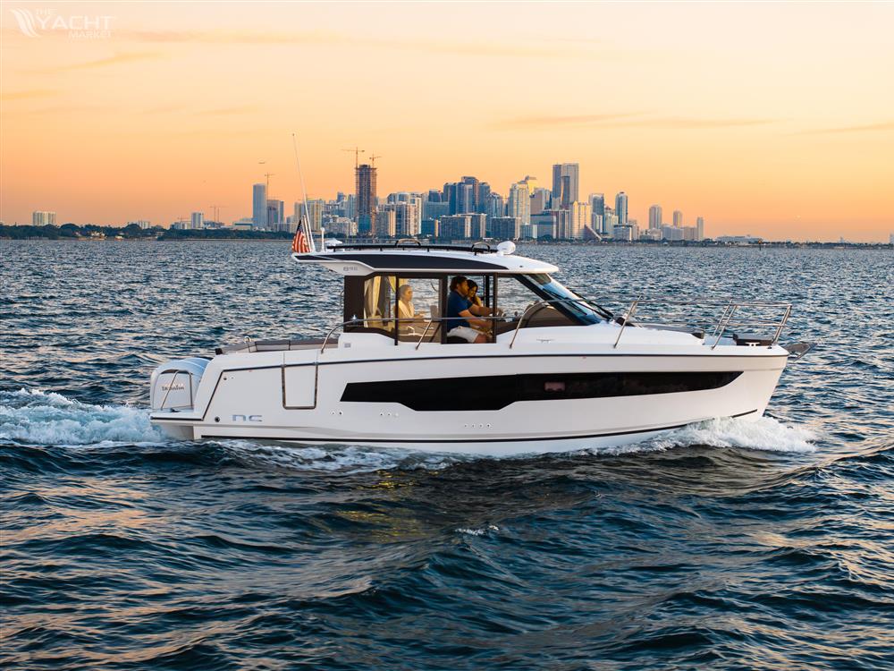 Jeanneau NC 895 S2 - 2025 Jeanneau NC 895 S2 cruising on water with city skyline at sunset.