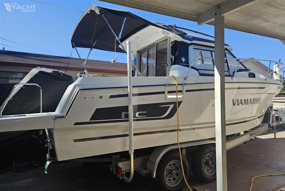 Jeanneau NC795 - 2023 Jeanneau NC795 boat on trailer under canopy, side view.