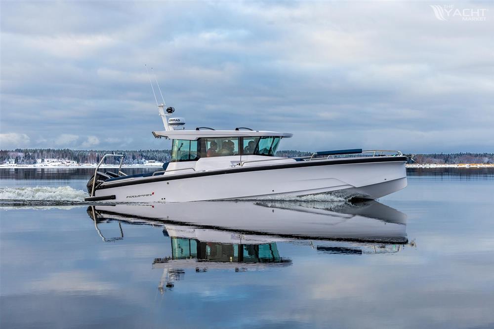Axopar 29 Cross Cabin - 2025 Axopar 29 Cross Cabin boat on calm water, reflecting sky and shoreline.