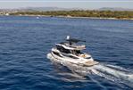 Galeon 430 Explorer - 2025 Galeon 430 Explorer yacht cruising on a serene blue sea near a lush coastline.