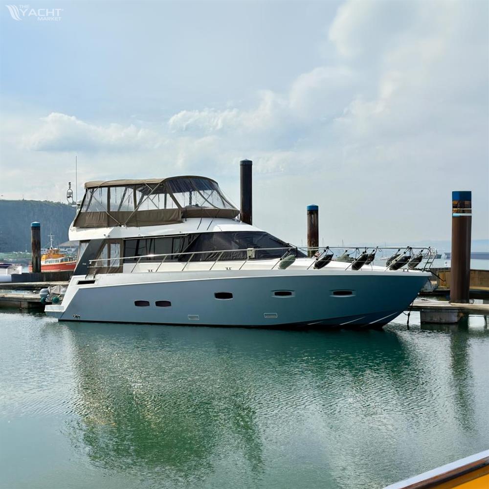 Sealine F46 - 2011 Sealine F46 yacht docked in a marina, calm water reflections, cloudy sky.