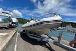 Zodiac Pro Open 650 - 2005 Zodiac Pro Open 650 boat on trailer by waterfront, under blue sky.