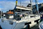 Dufour 41 - 2025 Dufour 41 sailboat docked, for sale, with flags and marina background.