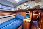 Moody 34 - Cozy cabin interior of a 1985 Moody 34 sailboat with blue bedding and wooden furnishings.