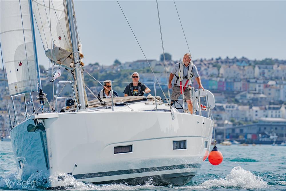 Dufour 390 - Sailing on a 2021 Dufour 390 yacht with crew, coastal town in background.