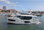 Absolute Navetta 53 - 2025 Absolute Navetta 53 yacht cruising in a marina with sailboats and buildings in the background.