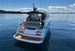 Fairline Targa 45 GT - 2025 Fairline Targa 45 GT yacht on calm water, rear view with flag.
