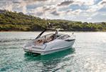 Fairline F//Line 33 - 2026 Fairline F//Line 33 yacht cruising on clear water near a lush, green coastline.