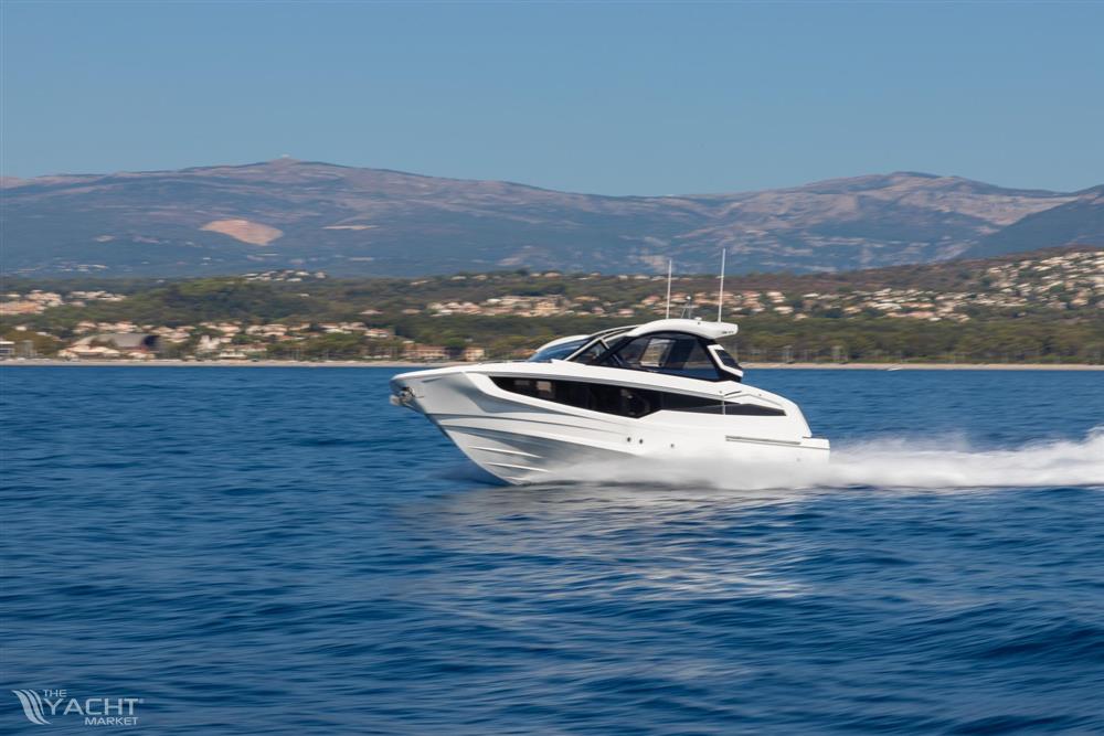 Galeon 335 GTO - 2025 Galeon 335 GTO yacht cruising on blue ocean with scenic mountain backdrop.