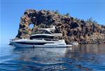 Galeon 640 Fly - 2018 Galeon 640 Fly yacht near rocky coastal arch, clear blue sky and water.